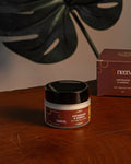 Jar and box of a product on a wooden surface with a leaf in the background