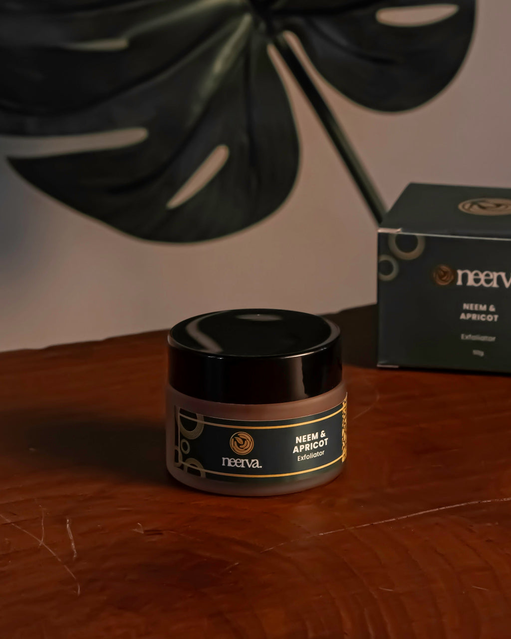 Jar of cream and box on a wooden surface with a leaf in the background