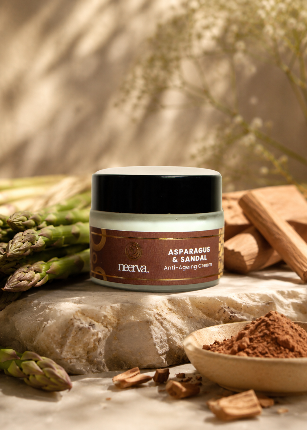 A jar of Neerva Asparagus & Sandal anti-aging cream styled on a stone slab with asparagus and sandalwood in a warm, natural setting.
