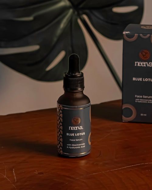 A small dark bottle and matching product box from the brand Neerva, placed on a wooden surface with a large dark monstera leaf behind them against a neutral wall.