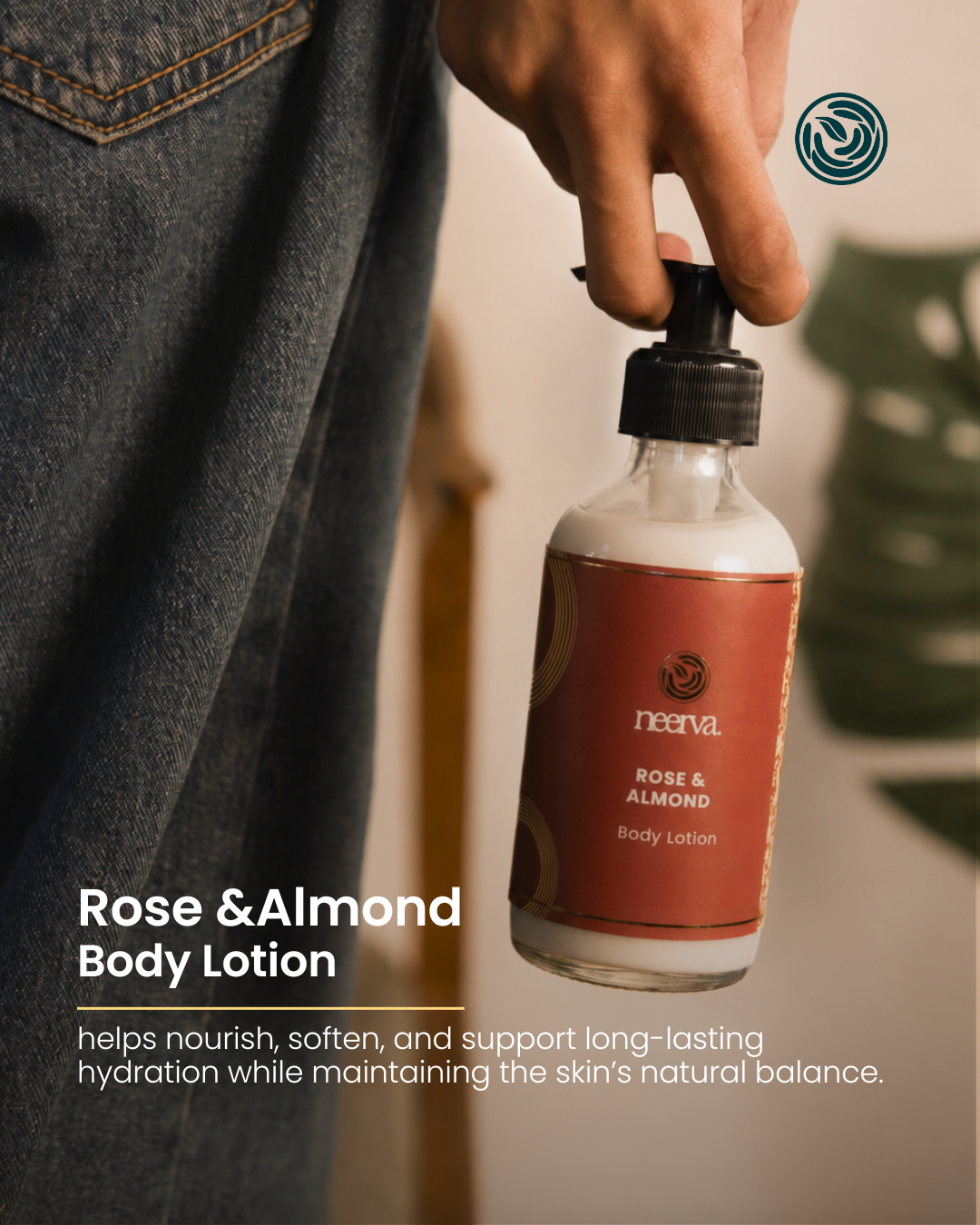 A hand holding a bottle of Neerva Rose & Almond Body Lotion against a softly blurred indoor background with denim jeans visible on the left.
